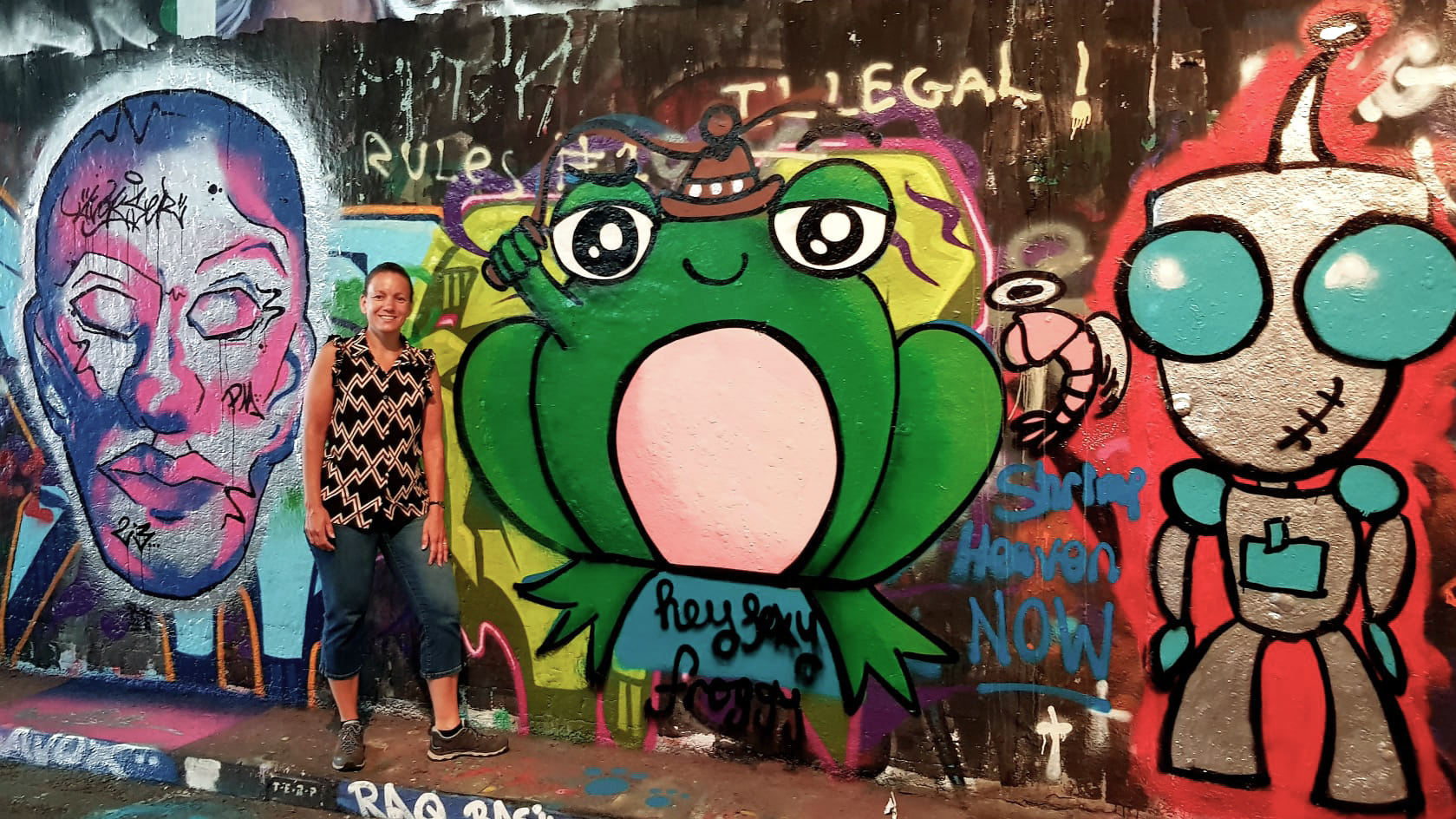 Inge van den Hoogen staat voor een muur met graffiti.